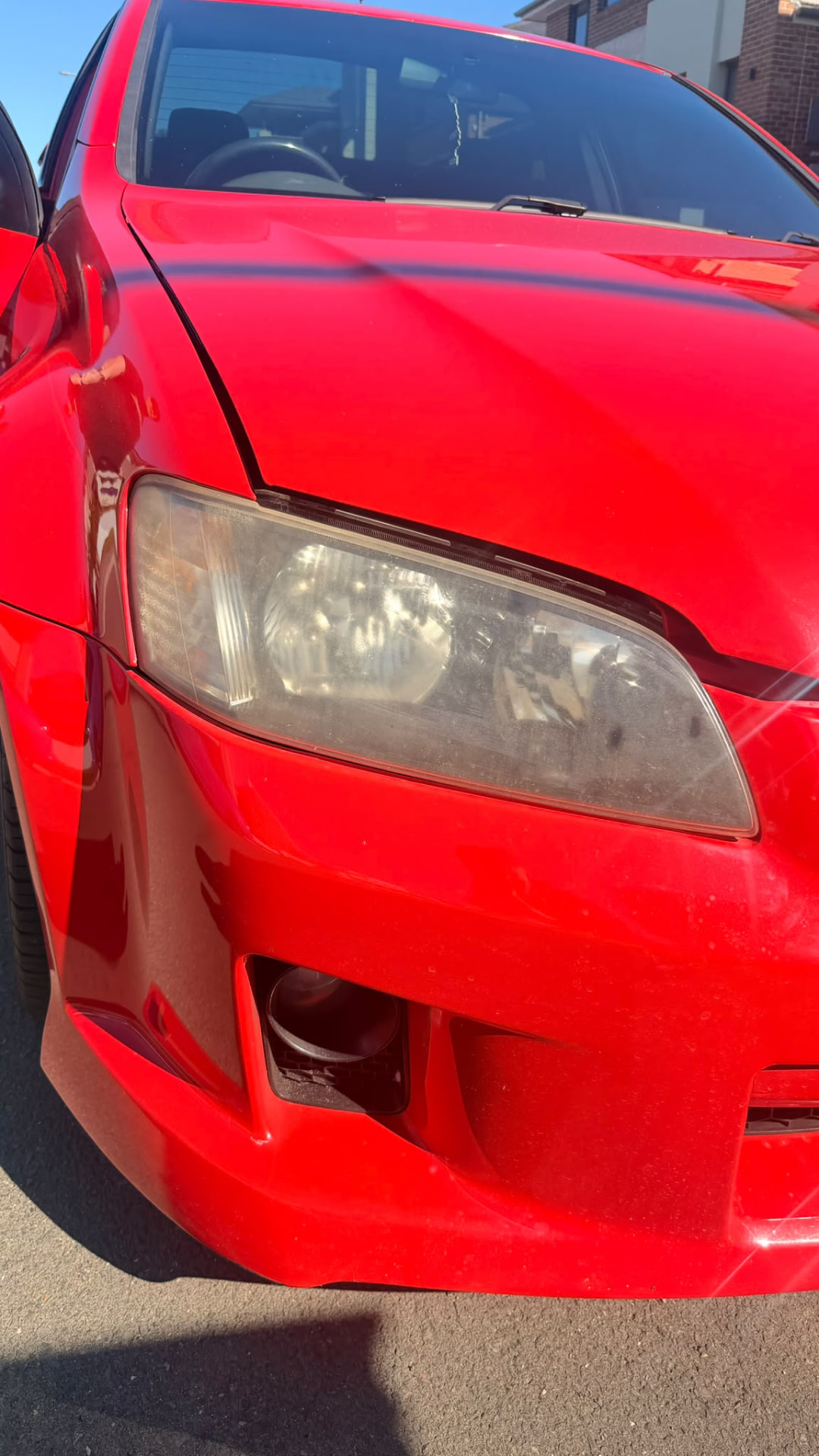 Red vehicle paint and headlight before restoration work